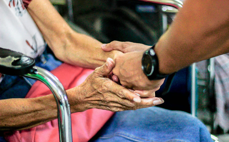 hands clasped between an old lady and a man